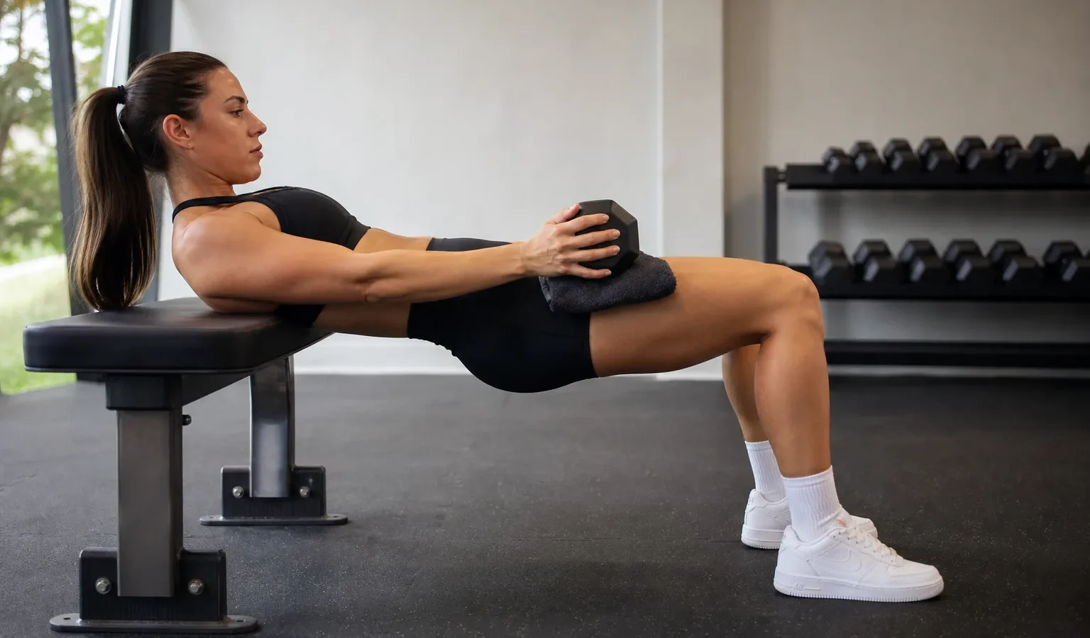 Hip thrust bez sztangi z hantlem na biodrach, łopatki oparte o ławkę